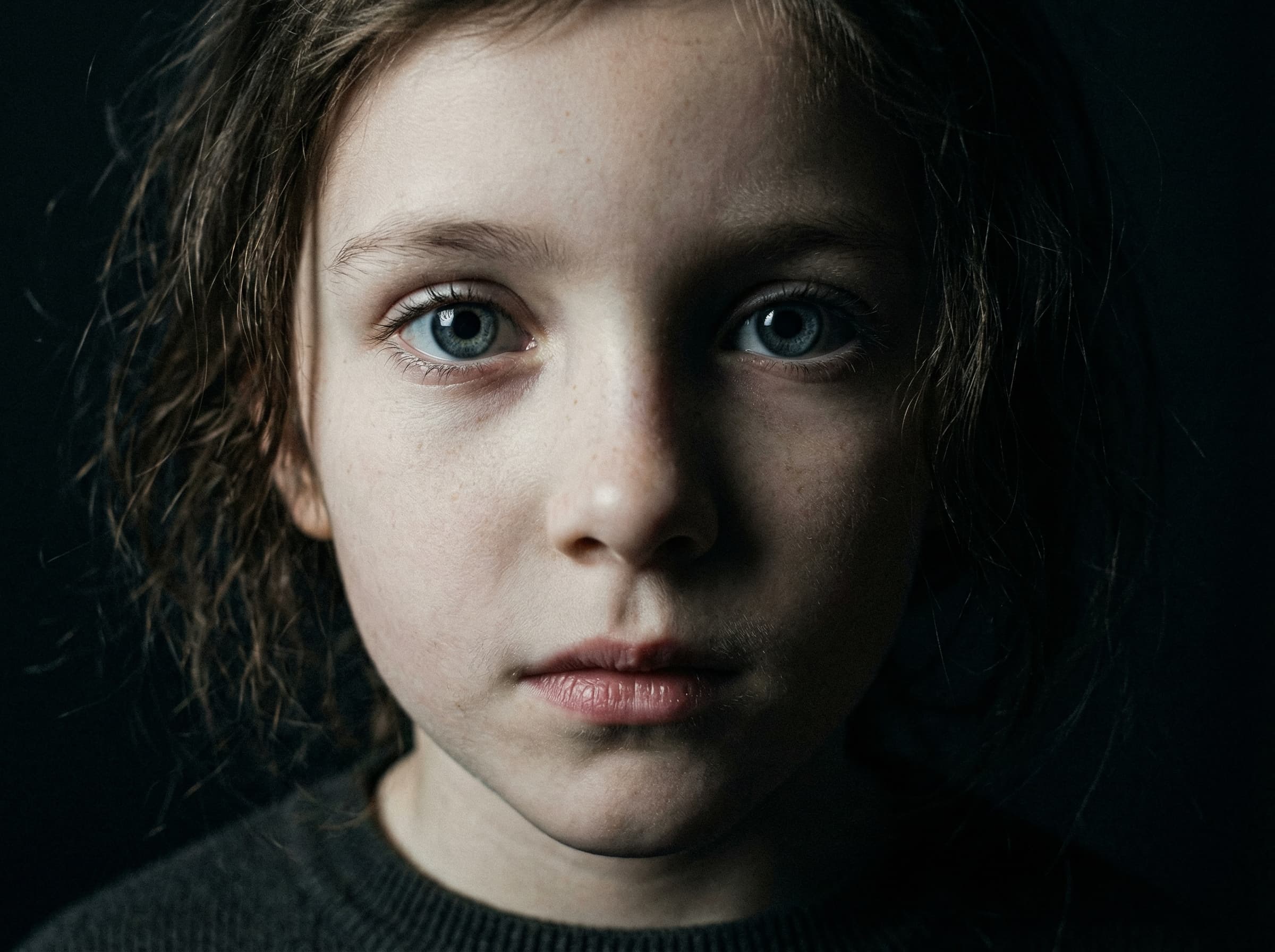 Close dramático do rosto de uma criança com olhos abertos, iluminação cinematográfica misteriosa